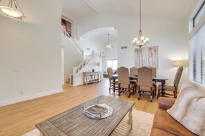 Un ampio soggiorno con un tavolino in legno, una zona pranzo con un lampadario e una scala che conduce a un piano superiore.