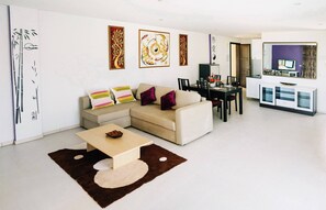 A modern living room with a sofa, coffee table, and dining area.