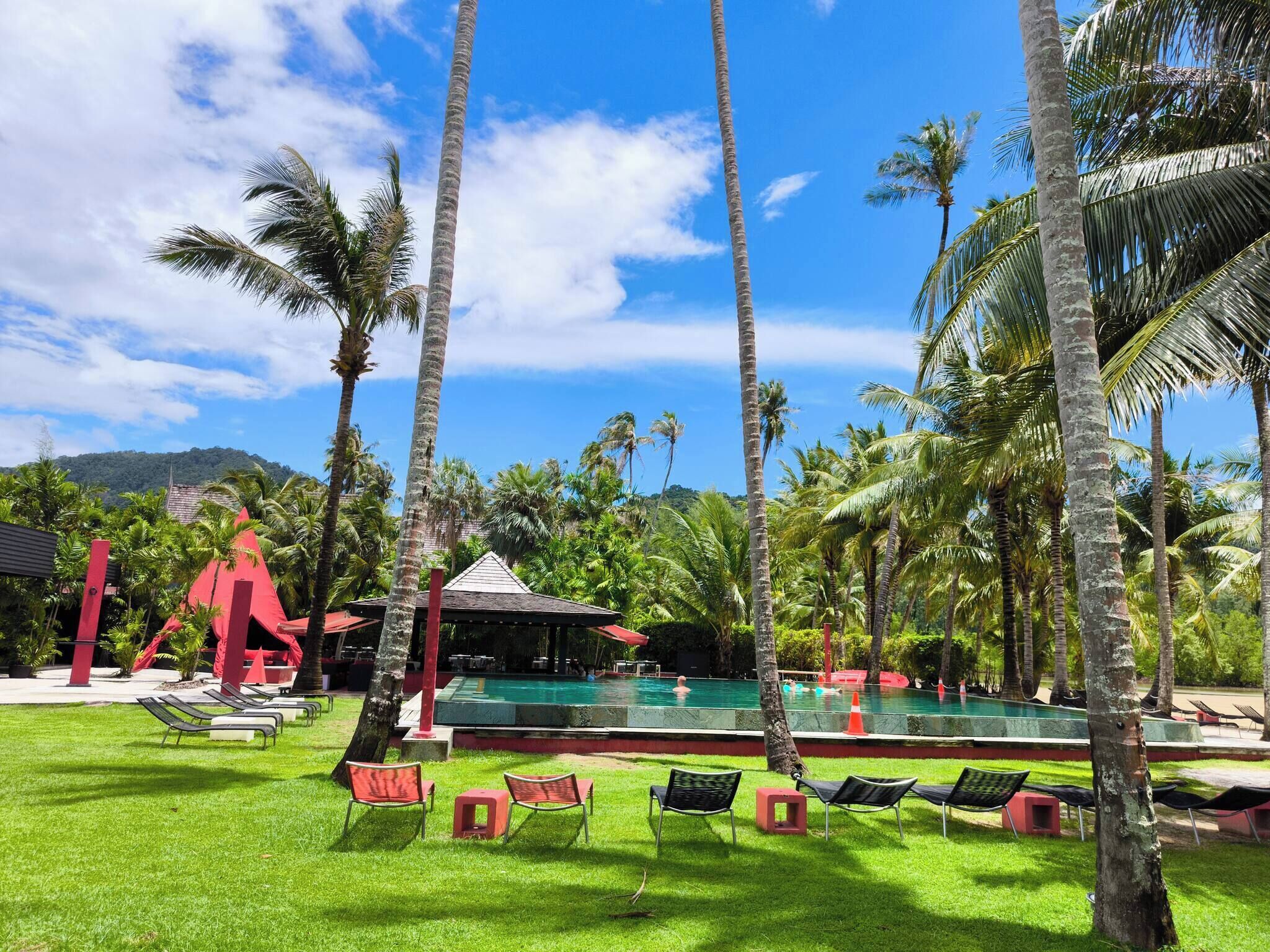 A pool area with lounge chairs and a red structure.