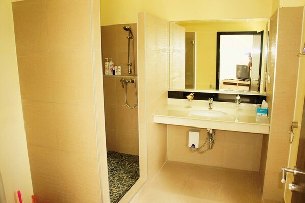 A bathroom with a shower, two sinks, a mirror, and toiletries on the wall.