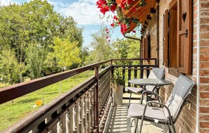 A balcony with a table and chairs, a wooden railing, and a brick wall. - Gorgeous home in Tugonica with WiFi (Tugonica)