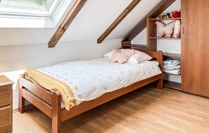 A single bed in a room with wooden beams, a window, and a wooden wardrobe. - Gorgeous home in Tugonica with WiFi (Tugonica)