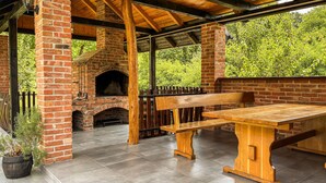 Un patio al aire libre con una chimenea de ladrillo, bancos de madera y una mesa.