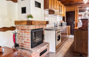 A kitchen with a brick fireplace, wooden cabinets, and a tiled backsplash. - Gorgeous home in Tugonica with WiFi (Tugonica)
