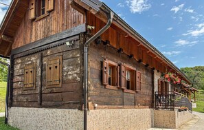 A wooden house with a stone foundation, multiple windows with heart-shaped cutouts, and a balcony with potted plants. - Gorgeous home in Tugonica with WiFi (Tugonica)