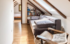 Ein gemütliches Schlafzimmer im Loft-Stil mit schrägem Dach, einer eingebauten Bücherwand, einem bequemen Sofa und einer hölzernen Bank.
