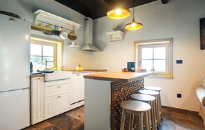Eine Küche mit weißen Schränken, einer Holz Arbeitsplatte und einer integrierten Bar mit Hockern.