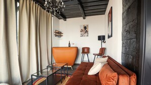 Ein modernes Wohnzimmer mit einer Couch, Sesseln, einem Glastisch und Kunstwerken an den Wänden.