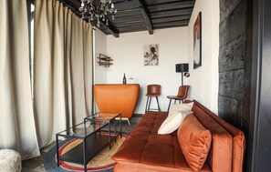 Ein modernes Wohnzimmer mit einer Couch, Sesseln, einem Glastisch und Kunstwerken an den Wänden.