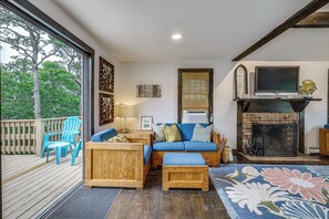Una sala acogedora con sofá de madera, sillas azules, chimenea y televisor.