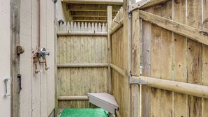 Una estructura de madera con una puerta de metal, un pequeño banco y un piso de césped artificial verde.