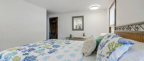Ein Schlafzimmer mit einem Bett, einem Nachttisch, einem Spiegel und einem Fenster mit Jalousien.