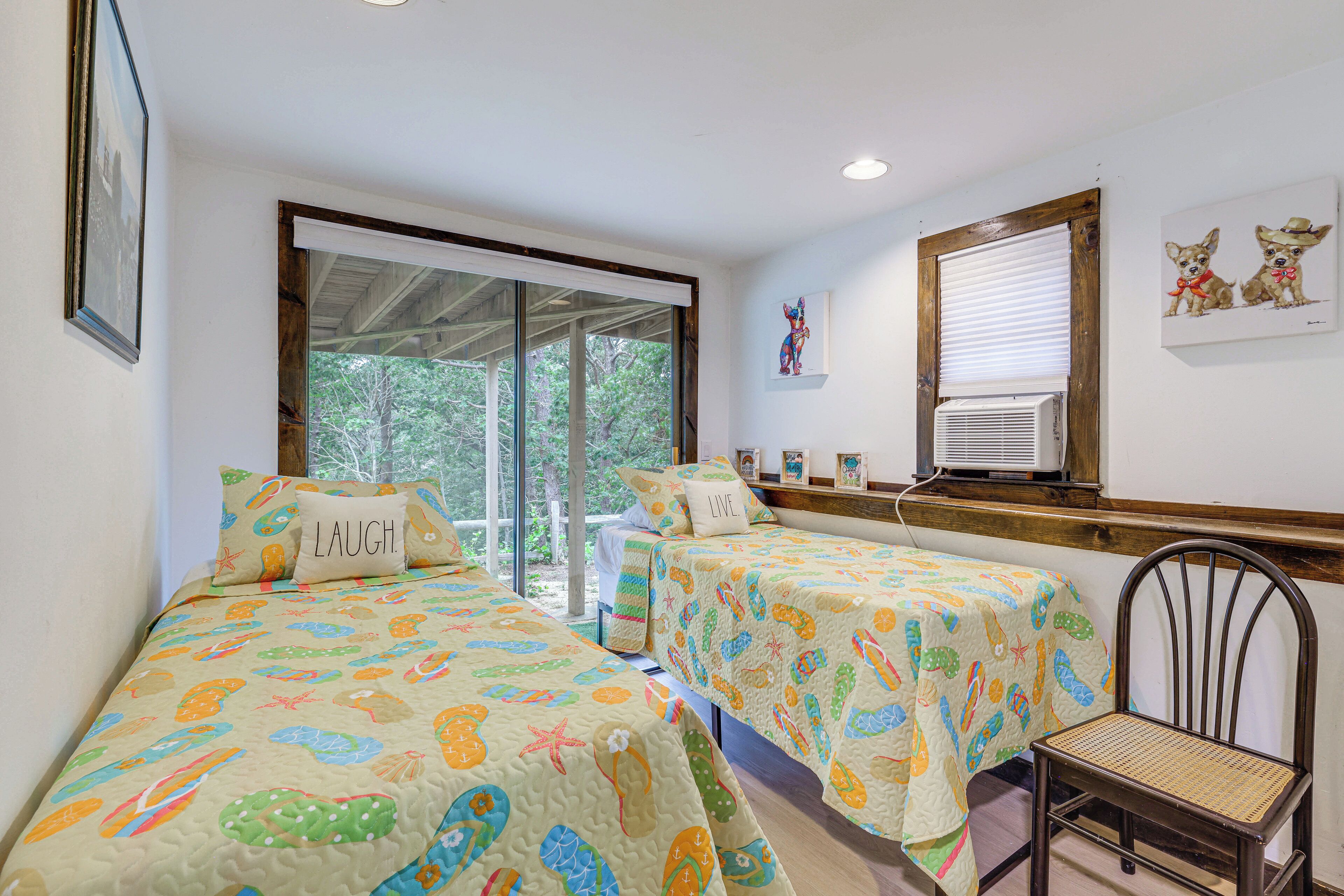 A room with two beds, a window, and a chair.