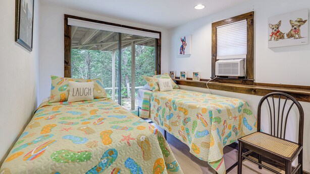 Una habitación con dos camas, una ventana y una silla.