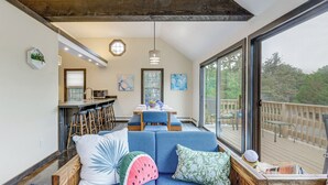 Un espacio de sala acogedor con un sofá azul, una mesa de comedor y una cocina al fondo.