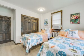 Un dormitorio con dos camas individuales, una puerta de madera, un radiador y un cuadro en la pared.