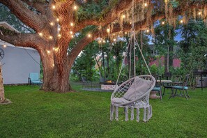A tree with hanging lights, a swing chair, and a fire pit in a grassy backyard. - 5 Mi to 3 Sisters Springs! Unit w/ Boat Parking (Homosassa)