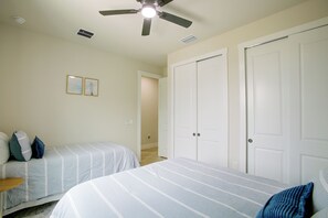 Ein Schlafzimmer mit zwei Betten, einem Deckenventilator und einer Tür zu einem anderen Raum.