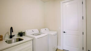 Un lavadero con dos lavadoras, un lavabo y una puerta.