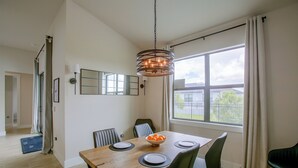 Un comedor con una mesa de madera, sillas, un frutero y una lámpara colgante.