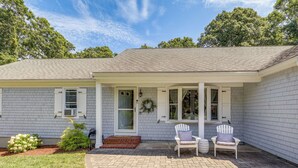 A single-story house with a covered porch, a small front yard, and a brick pathway leading to the entrance. - Minutes Away From the Best Beaches in Cape Cod! (South Dennis)