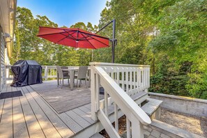 A wooden deck with outdoor furniture, a barbecue grill, and a red umbrella. - Minutes Away From the Best Beaches in Cape Cod! (South Dennis)