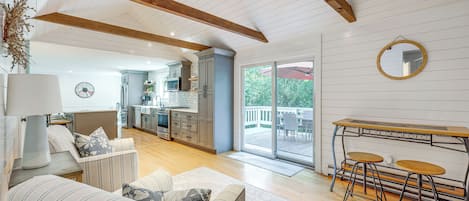 A spacious living area with a sofa, a dining table with chairs, and a kitchen in the background.