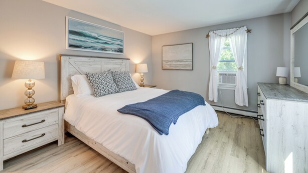 A bedroom with a bed, bedside tables, a dresser, and a window with curtains. - Minutes Away From the Best Beaches in Cape Cod! (South Dennis)