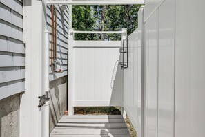 A white gate with a metal latch, a concrete step, and a metal pipe on the left. - Minutes Away From the Best Beaches in Cape Cod! (South Dennis)