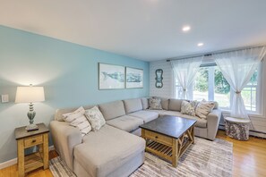 Ein Wohnzimmer mit Ecksofa, Couchtisch, Lampe und Kunstwerken an der Wand.