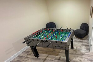 Uma mesa de futebol de bolso em um quarto com duas cadeiras e uma porta.