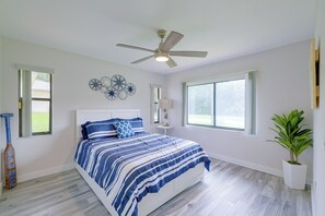 Ein Schlafzimmer mit einem Bett, einem Deckenventilator, einem Fenster und einer Pflanze.