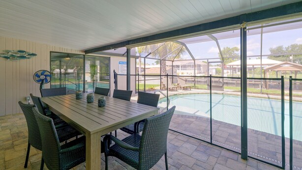 Um pátio externo com piscina, mesa e cadeiras.