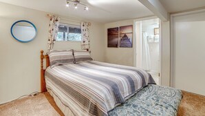 A bedroom with a bed, a round mirror, a window with curtains, and artwork on the wall. - Walk to Beach! Home w/ Sunroom in Anchor Bay (Gualala)