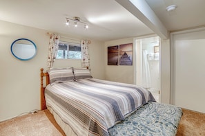 Ein Schlafzimmer mit einem Bett, einem runden Spiegel, einem Fenster mit Vorhängen und Bildern an der Wand.