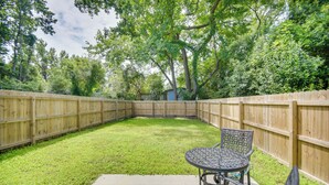 A backyard with a wooden fence, a grassy lawn, and a metal table with chairs. - Walk to Convention Center & Ocean! Extended Escape (Virginia Beach)