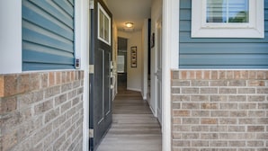 A hallway with a door leading to a kitchen, a staircase, and a window with blinds. - Walk to Convention Center & Ocean! Extended Escape (Virginia Beach)