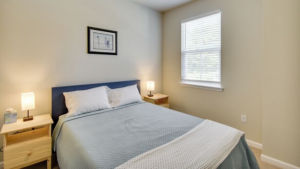A bedroom with a bed, two bedside tables, a nightstand, a window with blinds, and a framed picture on the wall. - Walk to Convention Center & Ocean! Extended Escape (Virginia Beach)