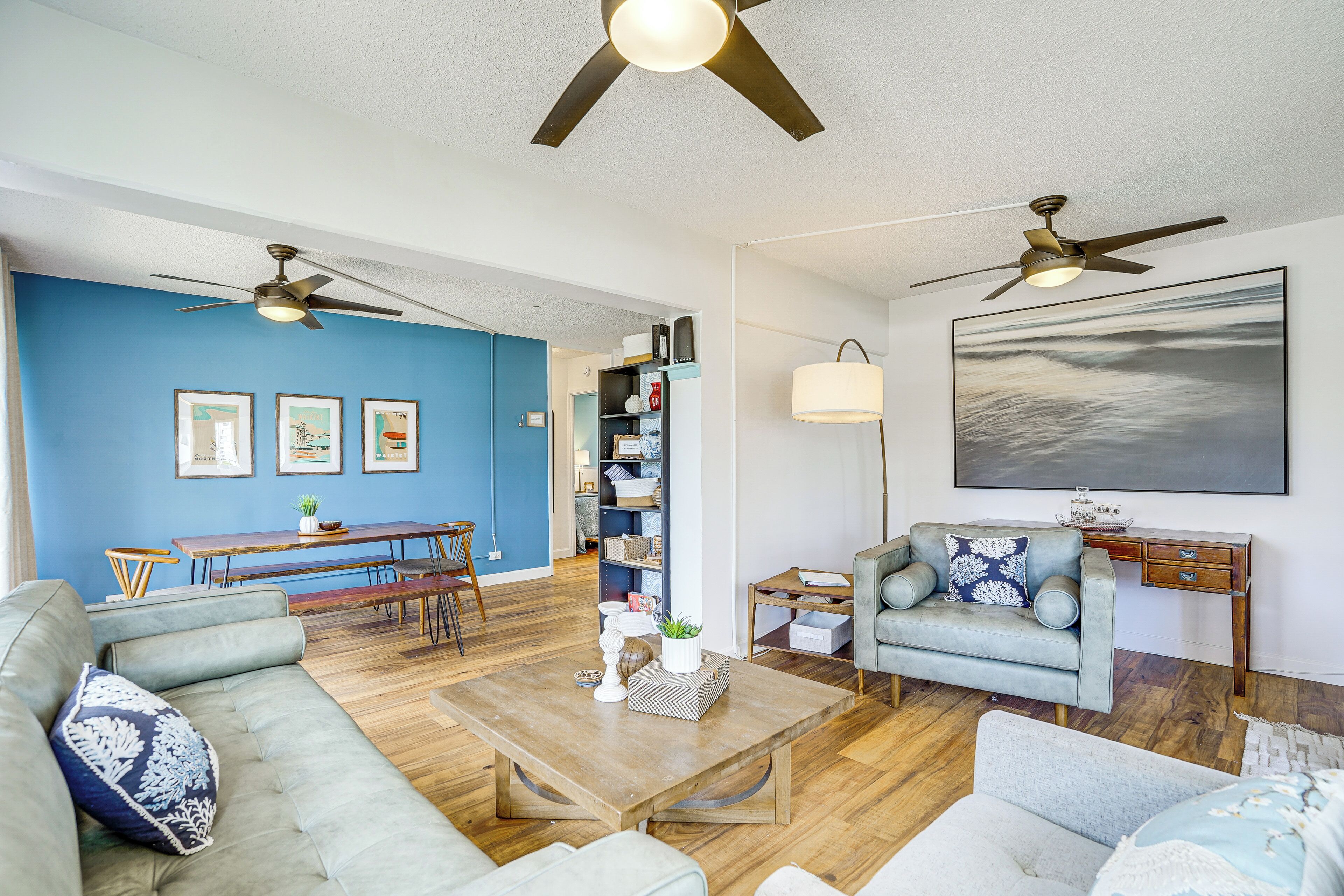 Uma sala de estar moderna com uma parede azul de destaque, uma área de jantar e um espaço de estar com uma mesa de centro.