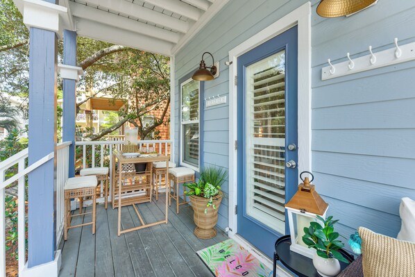 Eine Veranda mit Korbmöbeln, einem Blumentopf und einer Fußmatte.