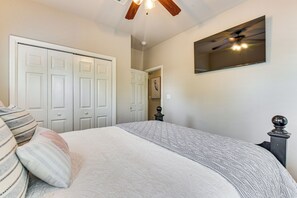 Ein Schlafzimmer mit Bett, Deckenventilator, Spiegel und Kleiderschrank.