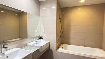 A bathroom with two sinks, a mirror, a shower, and a bathtub.