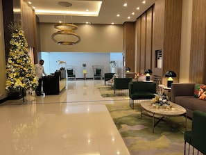 Eine moderne Hotellobby mit einer Rezeption, einer grünen Sitzgelegenheit und einem Weihnachtsbaum.