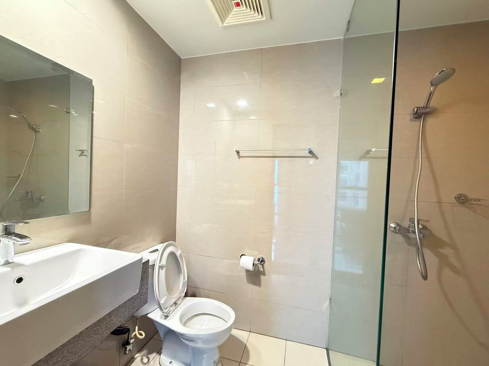 A modern bathroom with a glass shower enclosure, a white toilet, and a sink with a mirror above it.