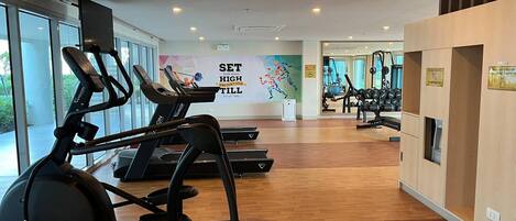 A gym with treadmills, exercise balls, and weights. There is a motivational poster on the wall and large windows.