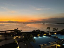 A pool area with a view of the sea and a sunset.