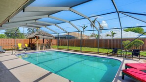 Piscina ao ar livre coberta, com espreguiçadeiras e uma estrutura com telhado de palha.