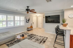 A modern living room with a sofa, coffee table, and a TV. There's a dining area with a bar and chairs. - Quiet Home 1 Mi to Savannas Preserve State Park! (Port St. Lucie)