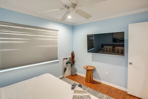 A bedroom with a bed, a ceiling fan, a window with blinds, a wall-mounted TV, a small wooden stool, and a rug. - Quiet Home 1 Mi to Savannas Preserve State Park! (Port St. Lucie)