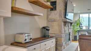 A kitchen with a stone wall, a built-in oven, a coffee maker, and a toaster. - Brand-New Luxury Lakefront Condo - 2200 Sq Ft! (Lake George)